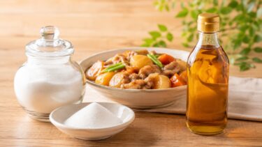 砂糖を入れたガラス瓶と小皿、みりんの瓶、肉じゃがの器が並んでいる