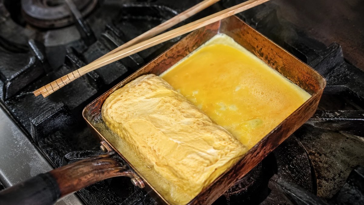 使い込んで飴色になった銅の卵焼き器で、だし巻き卵を巻いているところ