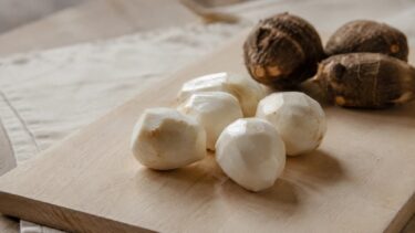皮をむいた里芋と、皮つきの里芋が木のまな板に並んでいる